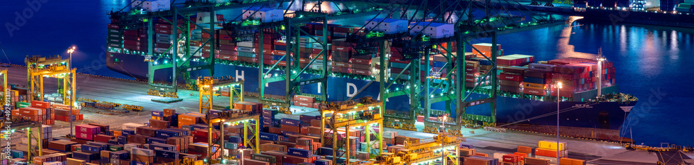 Banner image of Singapore container yard full of containers and container ship at night.