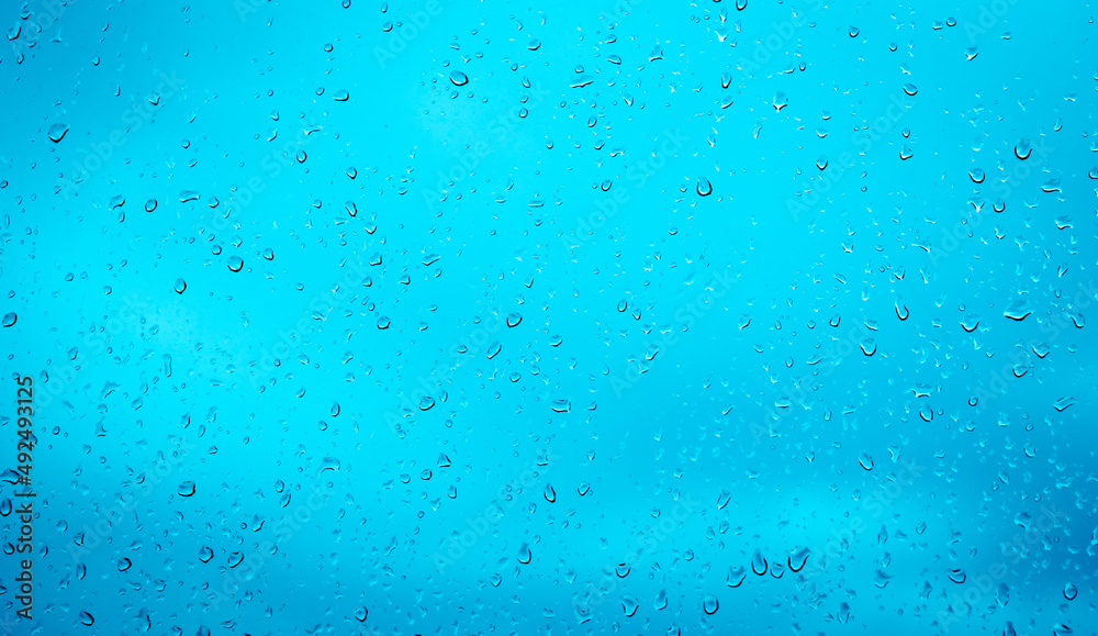 Rain drops, water drops of rain on a window glass blue background, abstract defocused with space Rain drops, water drops of rain on a window glass blue background, abstract defocused with space
