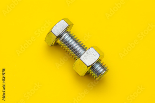 Bolt Nut abstract, isolated on a bright yellow background, threaded metal fastener. Workshop, manufacturing and building.