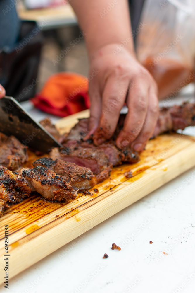 carne asada cortada  sobre tabla de madera .

manos cortando carne sobre tabla de madera con cuchillo.
