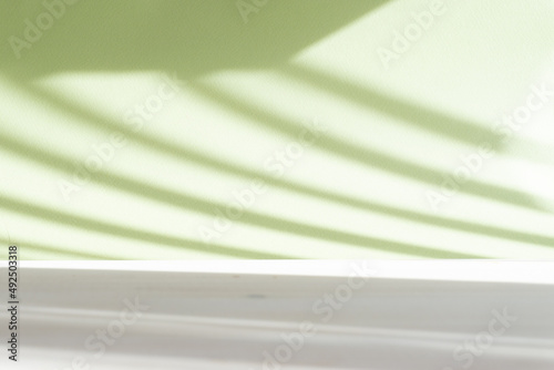 Minimalistic abstract textured background for presentation of cosmetic product. Greenish-white desktop wallpaper, with shadow in form of horizontal stripes