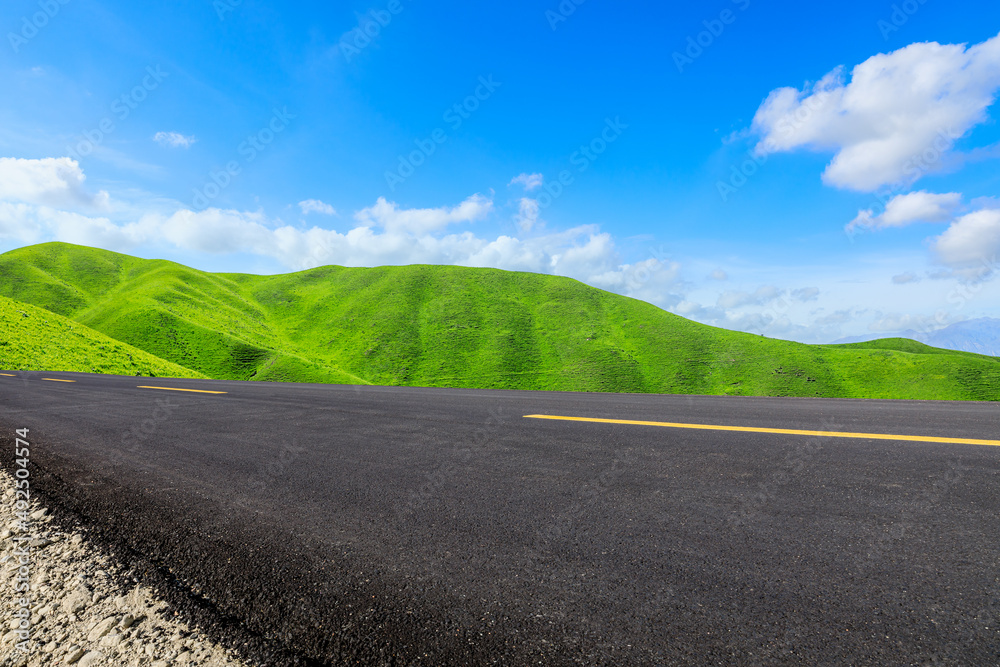 Fototapeta premium Empty asphalt road and green mountain nature scenery under blue sky