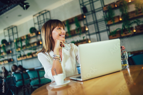 Young woman sitting in cafeteria and using credit card for online shopping