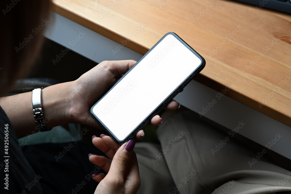 Woman hands holding mobile phone with white empty display for graphic display montage. Close up. Woman hands holding mobile phone with white empty display for graphic display montage. Close up.