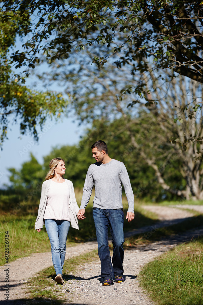 Its a perfect day for love. Full length shot of a young couple walking hand in hand in a park.