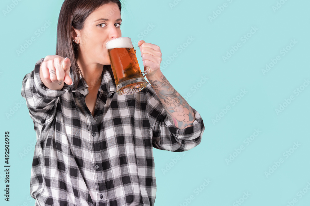 Tough woman with tattooed arm drinking a mug of beer Tough woman with tattooed arm drinking a mug of beer