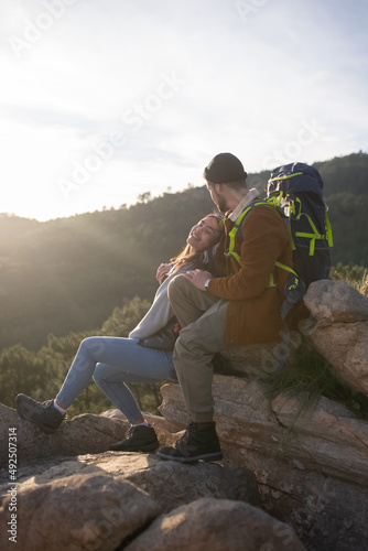 Couple resting after hiking in autumn. Man and woman in casual clothes with hiking ammunition sitting at peak, relaxing. Nature, activity, hobby concept