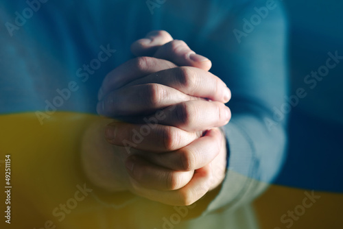 Close-up on ukrain flag with praying hands © erika8213