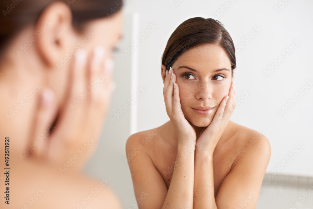 Smooth, flawless skin. A gorgeous young woman looking at her reflection in the mirror with her hands on her face. Smooth, flawless skin. A gorgeous young woman looking at her reflection in the mirror with her hands on her face.