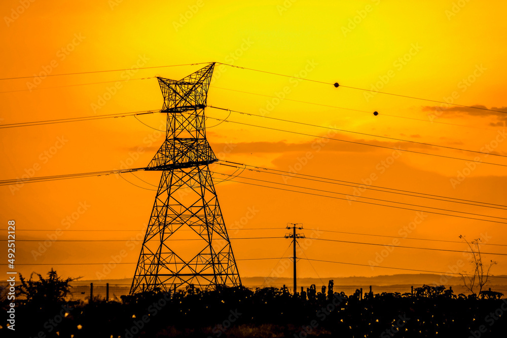 Fototapeta premium Power lines against a radiant sunset in rural Kenya