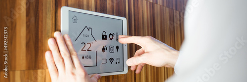 man controls smart home devices using digital tablet with launched application on background of wall. concept of digitalization. climate control system © Natalia