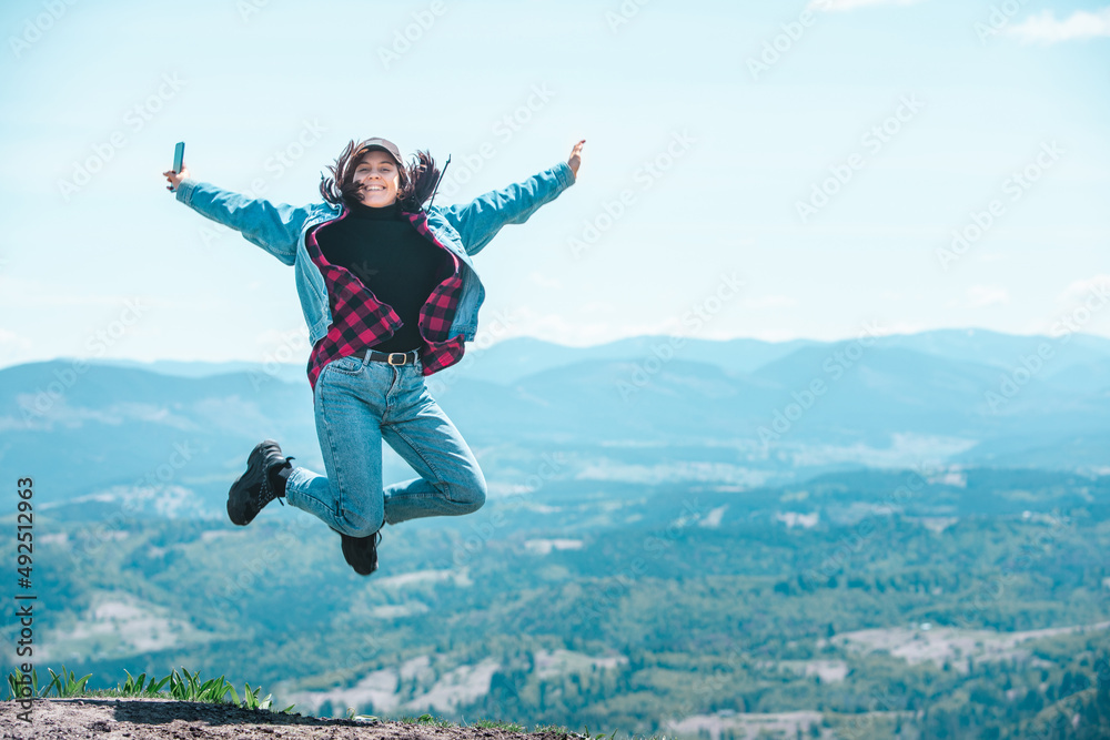 young pretty woman jumping at the top of the mountain