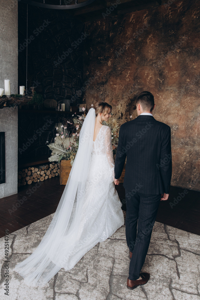 The first meeting of the groom in a black suit and the bride in a white wedding dress with a bouquet in the interior of a photo studio, hotel, on black background The first meeting of the groom in a black suit and the bride in a white wedding dress with a bouquet in the interior of a photo studio, hotel, on black background