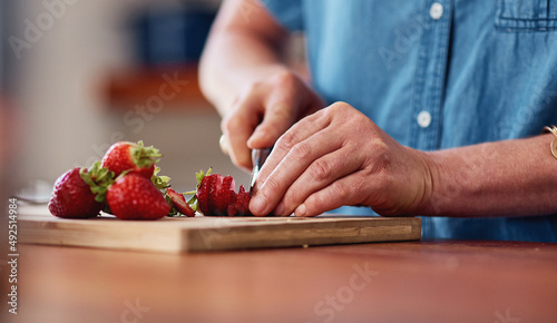 Every fruit salad needs strawberries. Cropped shot of an unrecognizable senior woman cutting up strawberries while preparing breakfast in her kitchen at home.