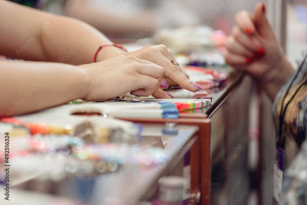 Fototapeta premium Closeup of female manicurist showing samples of nail polish to female client