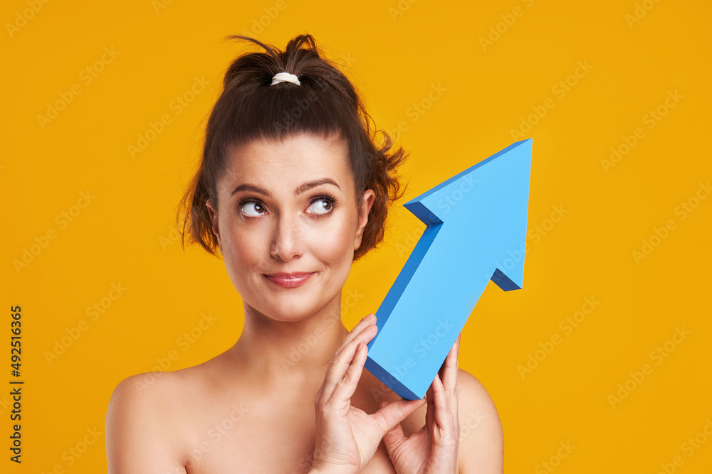 Studio shots of beautiful young woman over yellow background with arrows Studio shots of beautiful young woman over yellow background with arrows