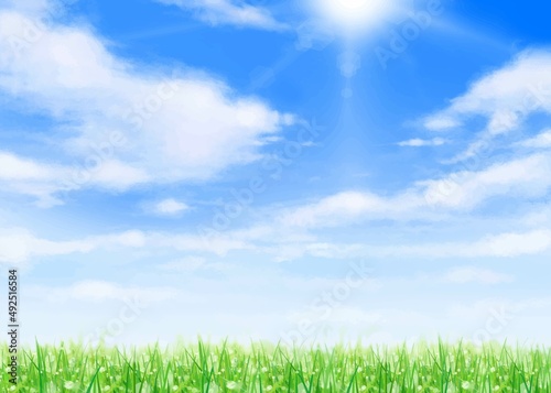 太陽の光が差し込む雲のある青空に芝生と新緑の美しい若葉の初夏フレーム背景素材