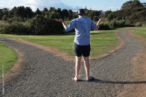 Man standing at a fork in a gravel path wondering which direction to take photo