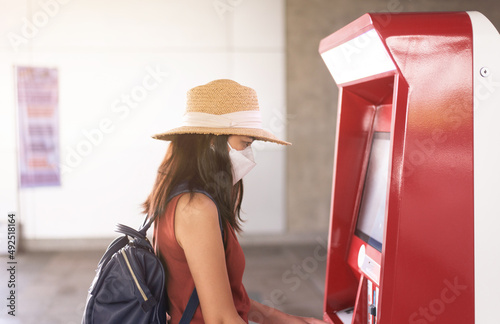 Woman passenger buying ticket with auromatic matchine at train station,Transport and insurance concept photo