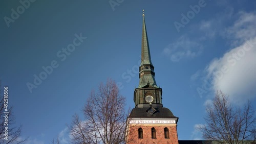 Mora Church Tower and Slow Moving Clouds on Blue Sky in Dalarna, Sweden, Low Angle photo