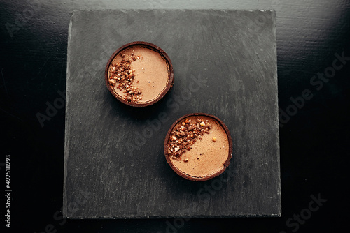 Shortbread tartlet with caramel and nuts, stone black board, chocolate, cocoa, walnut, texture photo