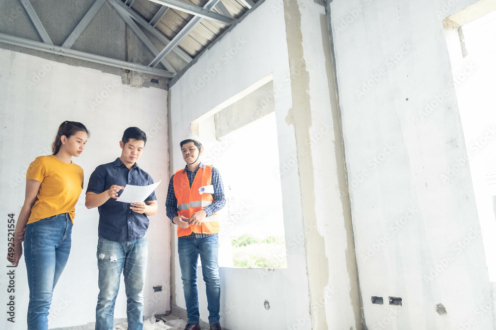 Fototapeta premium asian couple checking house with foreman engineering home inspection building house Walk home inspection with looking and pointing construction for check building home on job site to construction 2021