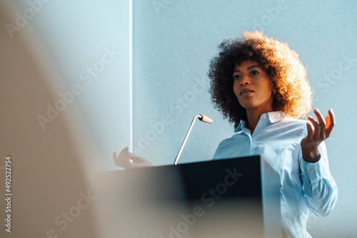 Businesswoman gesturing giving speech at work place photo