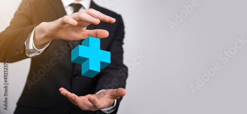 Businessman hold 3D plus icon, man hold in hand offer positive thing such as profit, benefits, development, CSR represented by plus sign.The hand shows the plus sign © Ivan