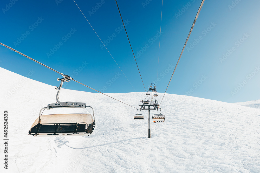 Cable cars on snow covered mountain on sunny day Cable cars on snow covered mountain on sunny day