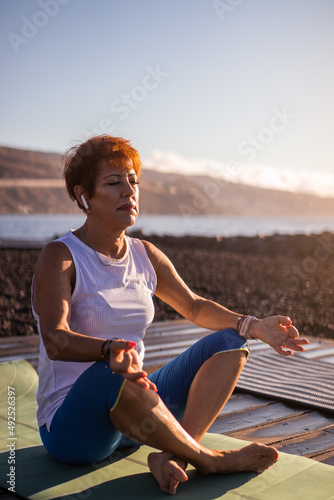 Senior woman doing meditation by the sea