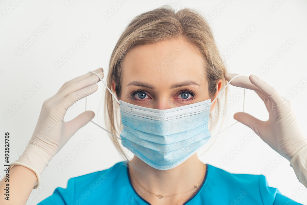 The proper way to put on and remove protective surgical mask demonstrated by young female doctor. High quality photo The proper way to put on and remove protective surgical mask demonstrated by young female doctor. High quality photo