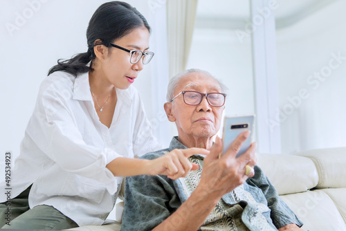 Old man using cellphone with his daughter on couch