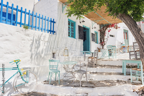 Beautiful traditional greek street with flowers and cafe tables on Amorgos island, Greece.
