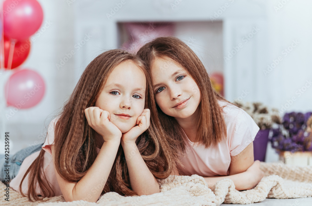 Two pretty little girls sisters happily cuddle and laugh Two pretty little girls sisters happily cuddle and laugh