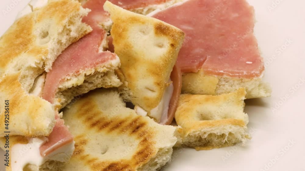 Sandwich leftovers, ham and cheese sandwich solid food waste rotating over white surface background, macro shot close up. Sandwich leftovers, ham and cheese sandwich solid food waste rotating over white surface background, macro shot close up.