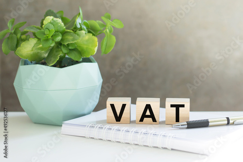 VAT 2022 on wooden cubes, notebook and a pen on a table. VAT 2022 - phrase from wooden blocks with letters, VAT 2022 concept