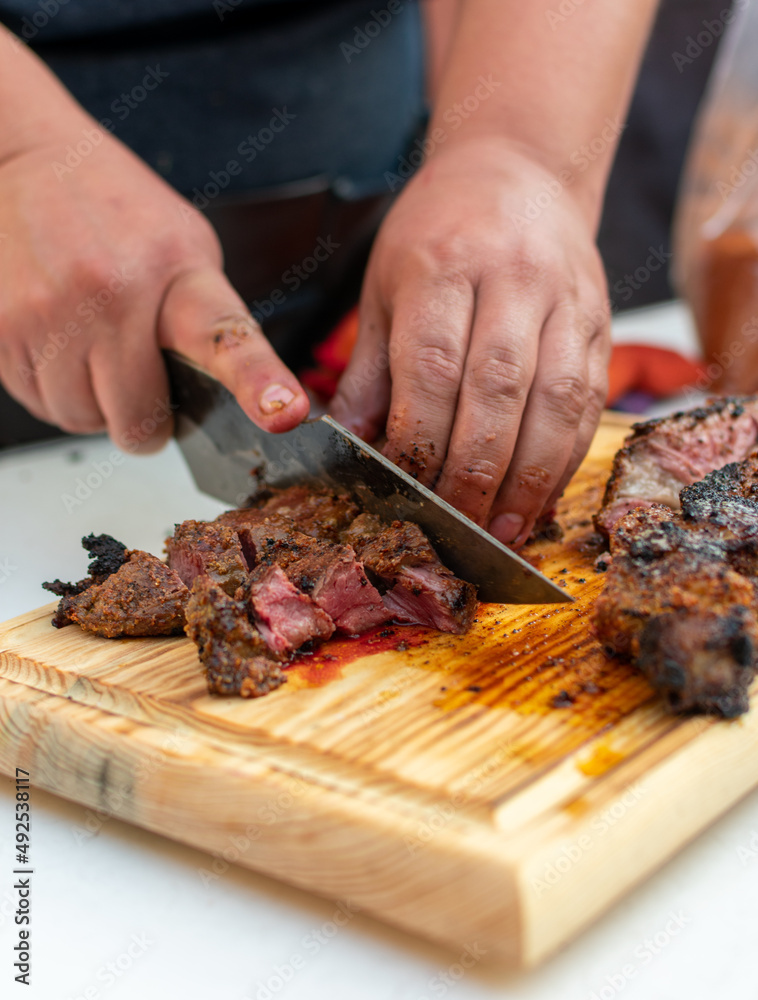 corte de res  T- bone.

T bone 

corte en el asador 

corte al carbón

manos cortando t- bone sobre tabla de madera. 