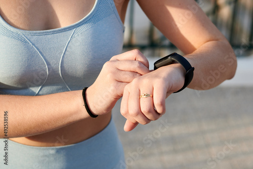 Close-up fitness woman looks at her electronc watch outdoors photo