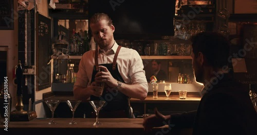 Caucasian male bartender mixing drinks behind the bar making cocktails photo