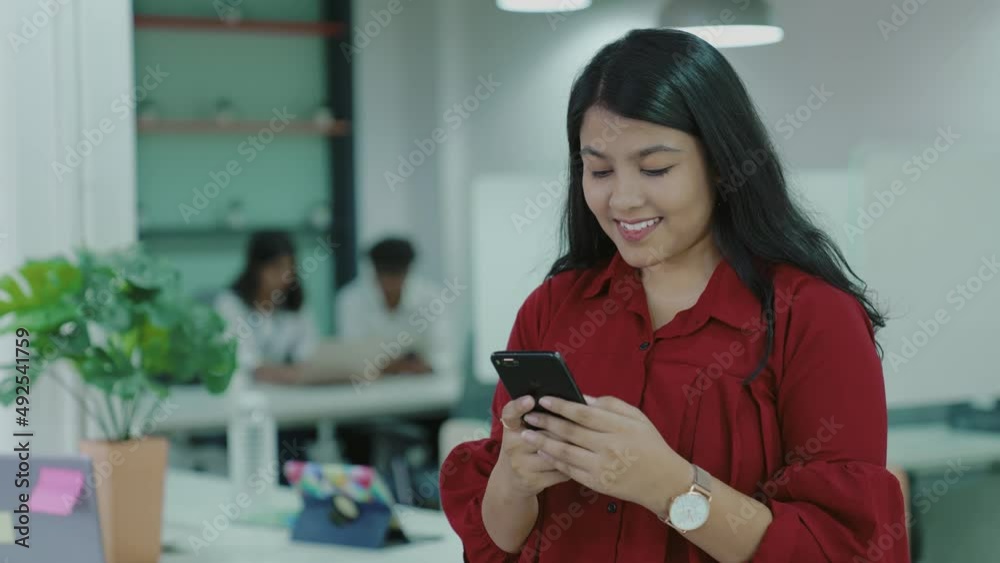 Young Indian woman while using smart phone for chatting with friends, family at home, office. smiling girl sitting on office desk and texting message on mobile phone. Young Indian woman while using smart phone for chatting with friends, family at home, office. smiling girl sitting on office desk and texting message on mobile phone.