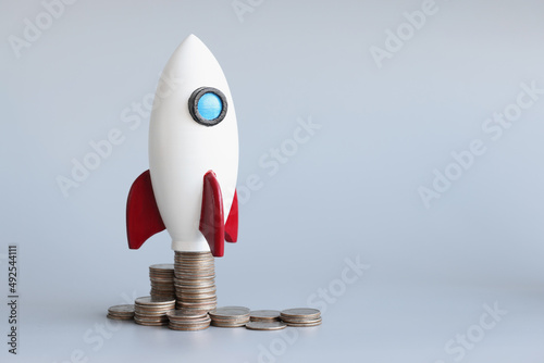 Fototapeta Naklejka Na Ścianę i Meble -  Miniature rocket stand on stack of coins, rocketship as symbol to open business project