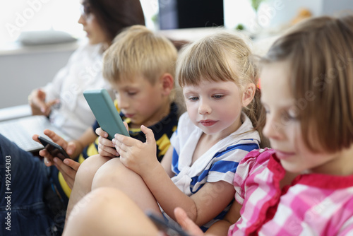 Children at home  stare at smartphone screens  addiction to modern technologies