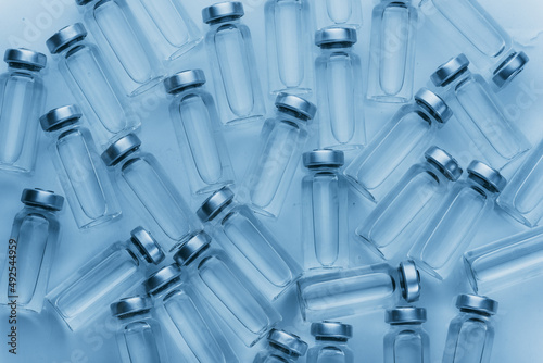 Glass medical ampoule vial for injection. Medicine is liquid sodium chloride with of aqueous solution in ampulla. Close up. Bottles ampule multicolor on background color and water. Human plasma.