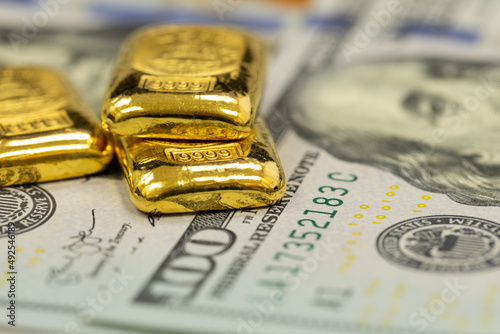 Φωτογραφία pile of pure gold bars, bullion, ingot on background of US dollar banknotes