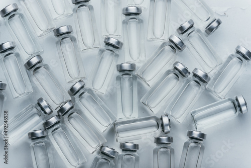 Glass medical ampoule vial for injection. Medicine is dry white drug penicillin powder or liquid with of aqueous solution in ampulla. Close up. Bottles ampule with aluminum cap on backgrounds gray. photo
