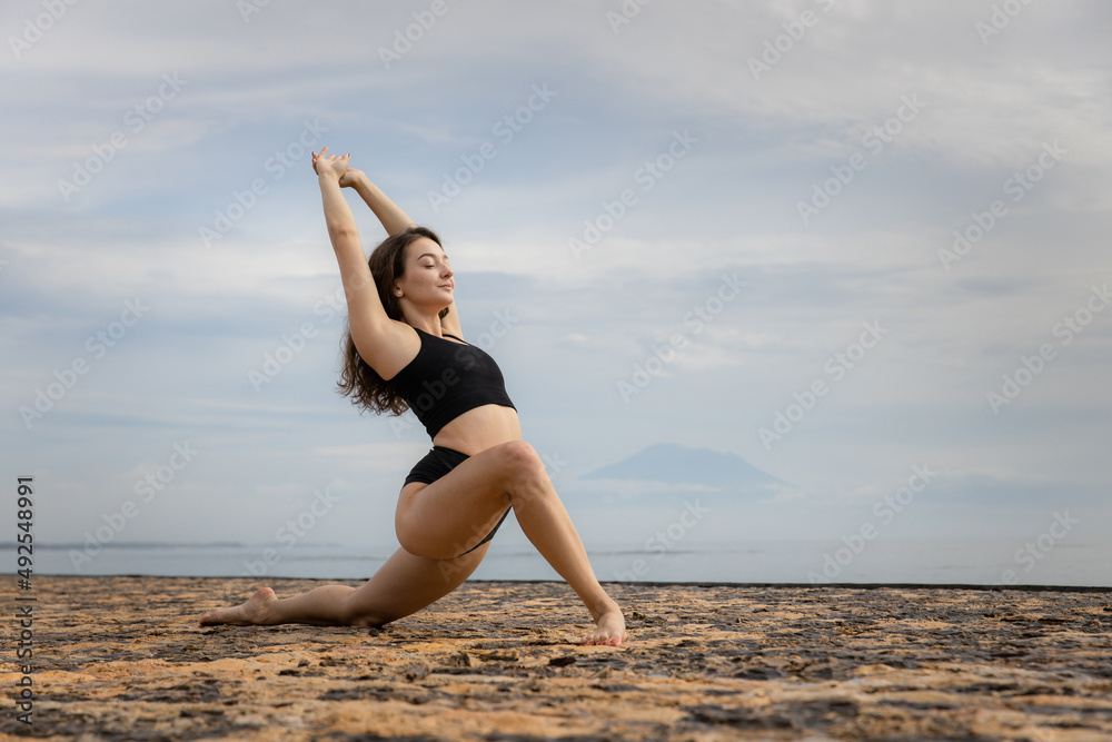 Stretching exercise in the morning. Sportive and athletic young female warming up on the beach. Fitness, sport, wellness concept. Healthy lifestyle. Active Caucasian woman workout. Bali