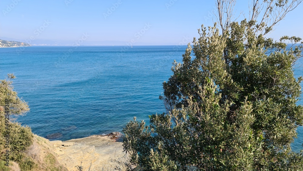 Savona, Italy - February 12, 2022: Panorama of the blue sea, light above the water, ocean sunrise. Some little waves in winter days. Clear sky reflected on the water. Savona, Italy - February 12, 2022: Panorama of the blue sea, light above the water, ocean sunrise. Some little waves in winter days. Clear sky reflected on the water.