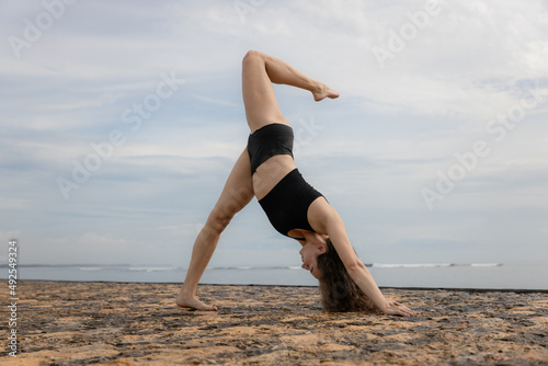 Outdoor yoga practice. Young woman practicing Parvatasana, Mountain pose. One leg up. Strong body, straight back. Healthy lifestyle. Cloudy background. Yoga retreat. Copy space. Bali
