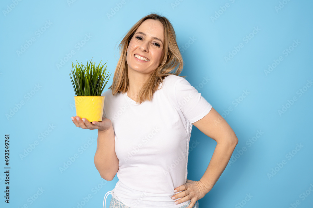 Obraz premium Young beautiful woman holding pot over blue isolated background with a happy face standing and smiling with a confident smile showing teeth