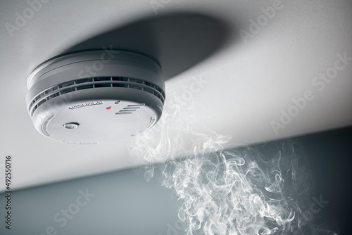 Smoke detector and interlinked fire alarm in action background photo